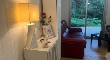 Intérieur chaleureux de Chez Léone à Naintré, Nouvelle-Aquitaine, FR avec canapé rouge et lampadaire.