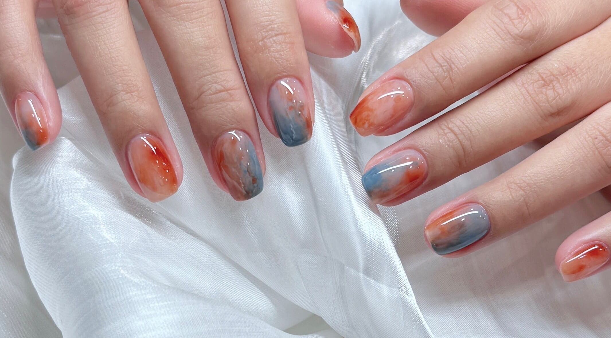 Elegant nail art in orange and blue hues at Woo Salon Studio, Arcadia, California, US.