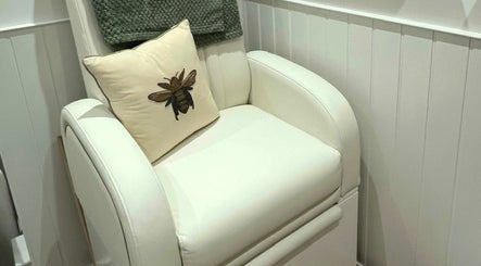 Comfortable white chair with bee cushion at Blooms Beauty Room, Burgess Hill, England, GB.