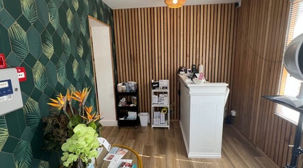 Reception area of Blooms Beauty Room, Burgess Hill, England with tropical plant decor and wooden accents.