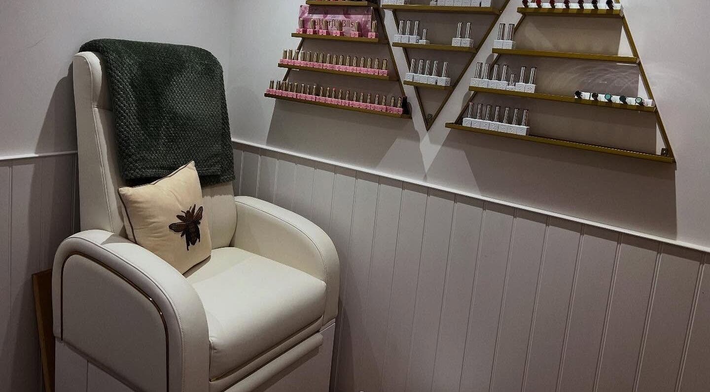 Cozy manicure chair in Blooms Beauty Room, Burgess Hill, England, GB with stylish shelves of nail products.