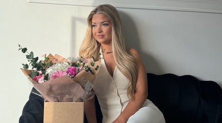 Woman with long blonde hair next to a floral bouquet at Adore Hair Extensions, Bristol, England, GB.