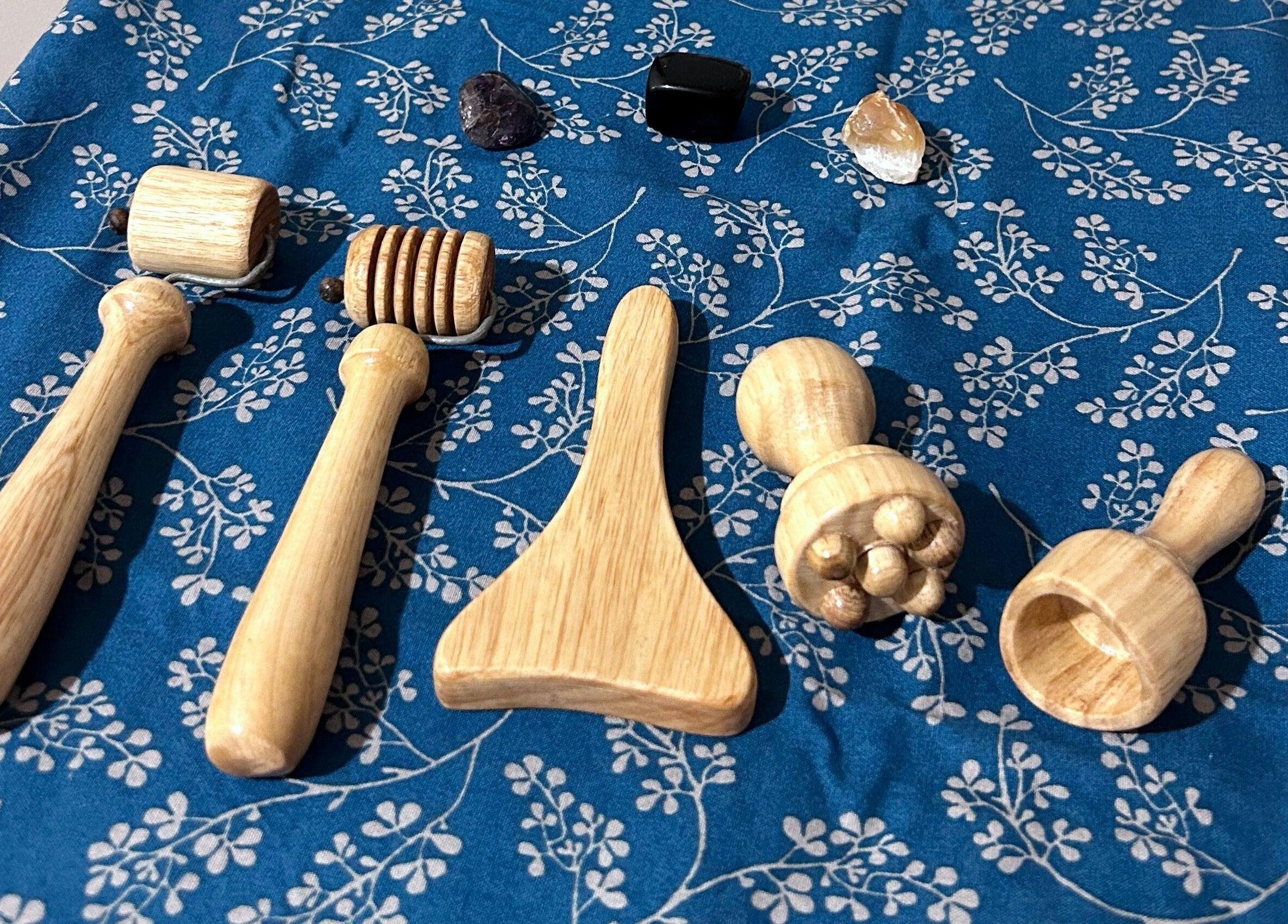 Outils de massage en bois chez Paü & Visage, Ripon, Québec, CA, sur une nappe bleue florale.