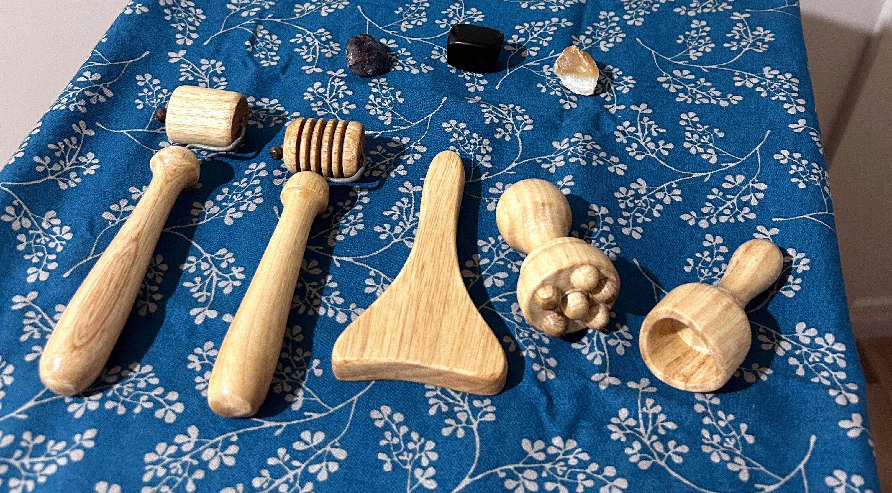 Outils de massage en bois chez Paü & Visage, Ripon, Québec, CA, sur une nappe bleue florale.
