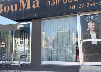 Front view of Bouma hair boutique, Nicosia, Lefkosia, CY, featuring glass windows and outdoor seating.