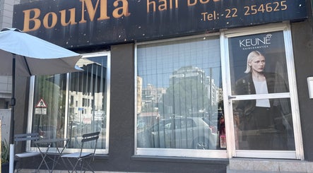 Front view of Bouma hair boutique, Nicosia, Lefkosia, CY, featuring glass windows and outdoor seating.