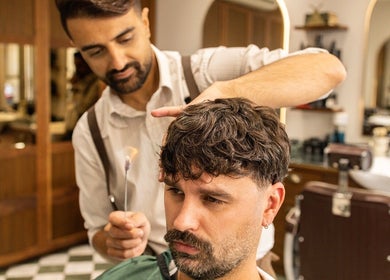 Barber styling hair at The Barbershop On Mill Street, London, England, GB.