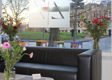Comfortabele zwarte bank met bloemen in Zzalon, Haarlem, Noord-Holland, NL, met uitzicht op de straat.