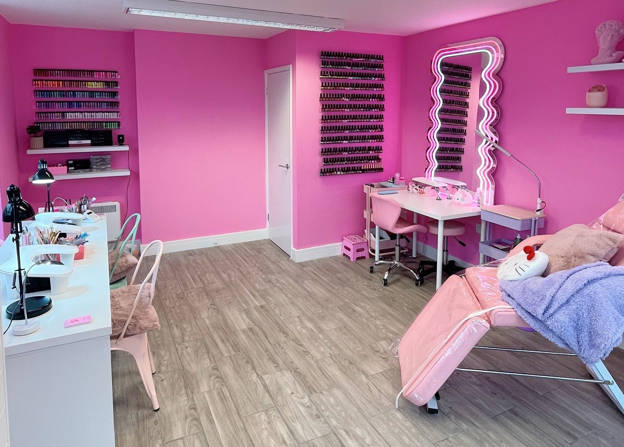 Bright pink interior of Nails With Soph, Eastbourne, England, GB featuring nail stations and cozy chairs.