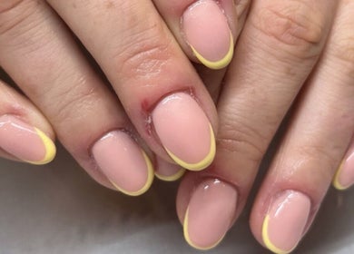 Stylish yellow-tipped manicure at Ems Beauty, Stockport, England, GB, showcasing expert nail artistry.