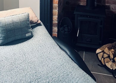 Relaxing corner at The Snug Room, Ravenfield, England, GB, featuring a plush bed and warm wood stove.