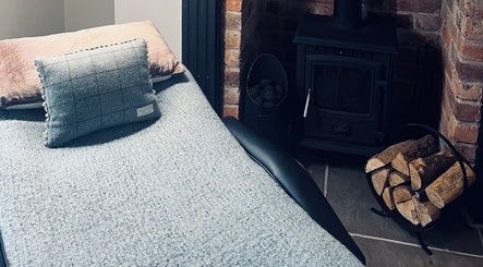 Relaxing corner at The Snug Room, Ravenfield, England, GB, featuring a plush bed and warm wood stove.