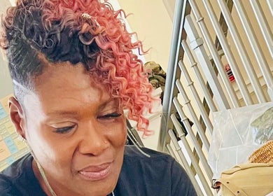 Stylist with vibrant curly hair at The Purple Door Styling & Grooming Lounge, Spartanburg, South Carolina, US.
