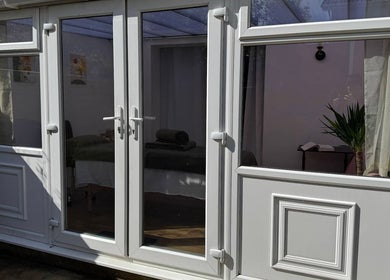 Entrance to Mia Wellness Room, Penryn, England, GB, with glass doors revealing a tranquil spa interior.