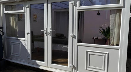 Entrance to Mia Wellness Room, Penryn, England, GB, with glass doors revealing a tranquil spa interior.