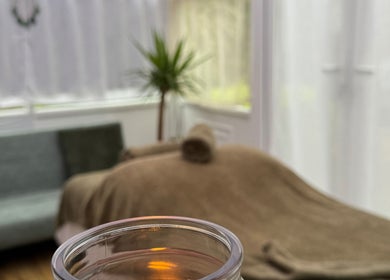 Cozy treatment room at Mia Wellness Room, Penryn, England, GB, featuring a massage table and lit candle.