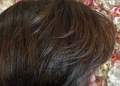 Elegant hairstyle showcasing smooth, glossy hair at D_A Hair Design in London, England, GB against a floral backdrop.
