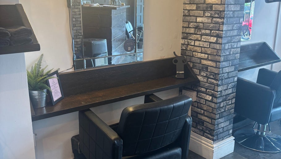 A sleek salon station at The Hair And Beauty Corner, Manchester, England, GB, with mirror and black chair.