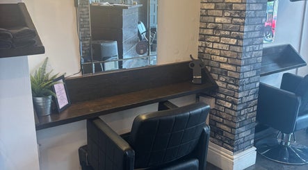 A sleek salon station at The Hair And Beauty Corner, Manchester, England, GB, with mirror and black chair.