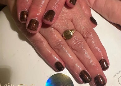 Shiny brown manicure at Cece Mol Beauty, York, England, GB. Hands rest under LED lamp.