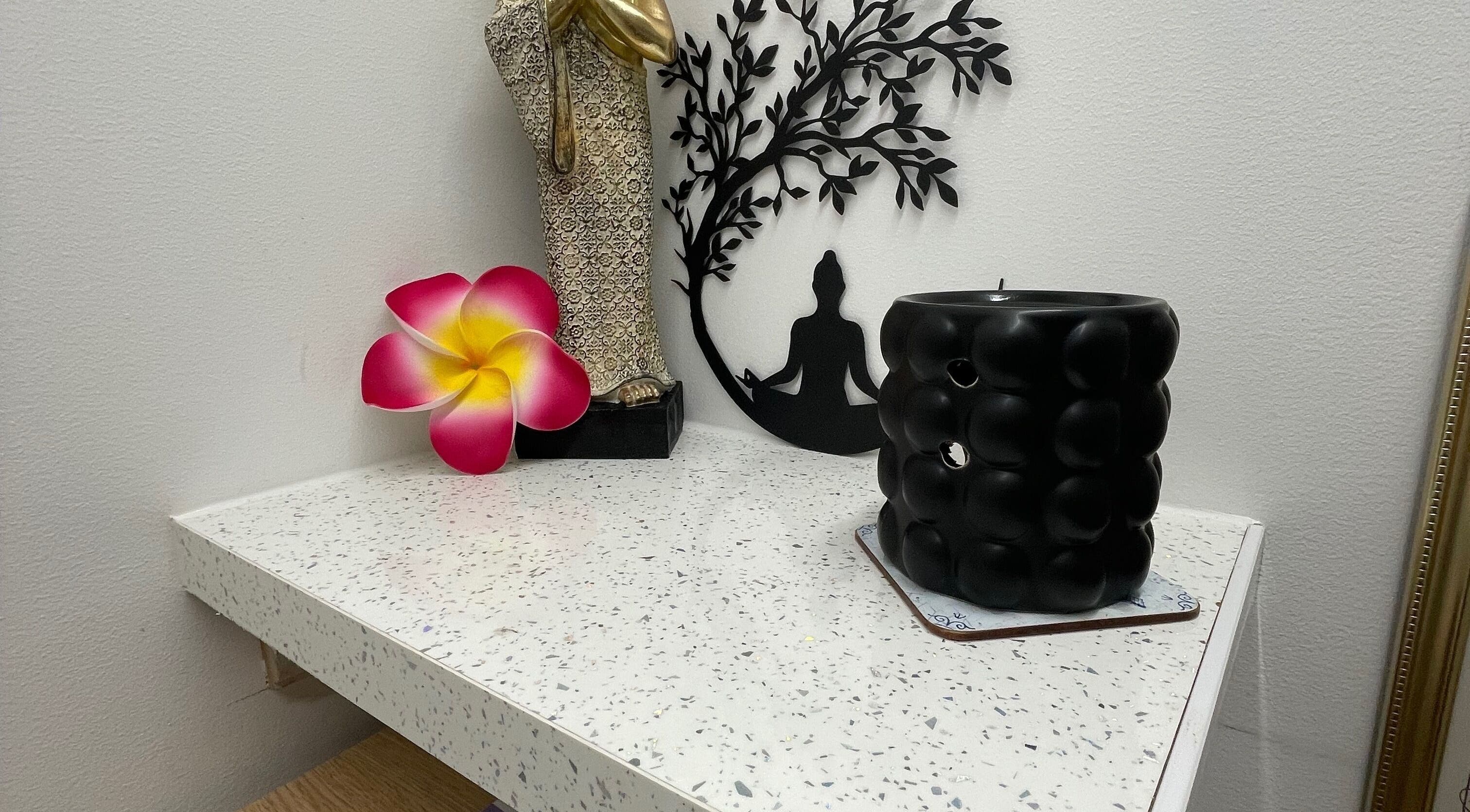 Peaceful decor at Wickham Thai Massage Therapy, Wickham, England, GB: statue, flower, and candid candle setup.