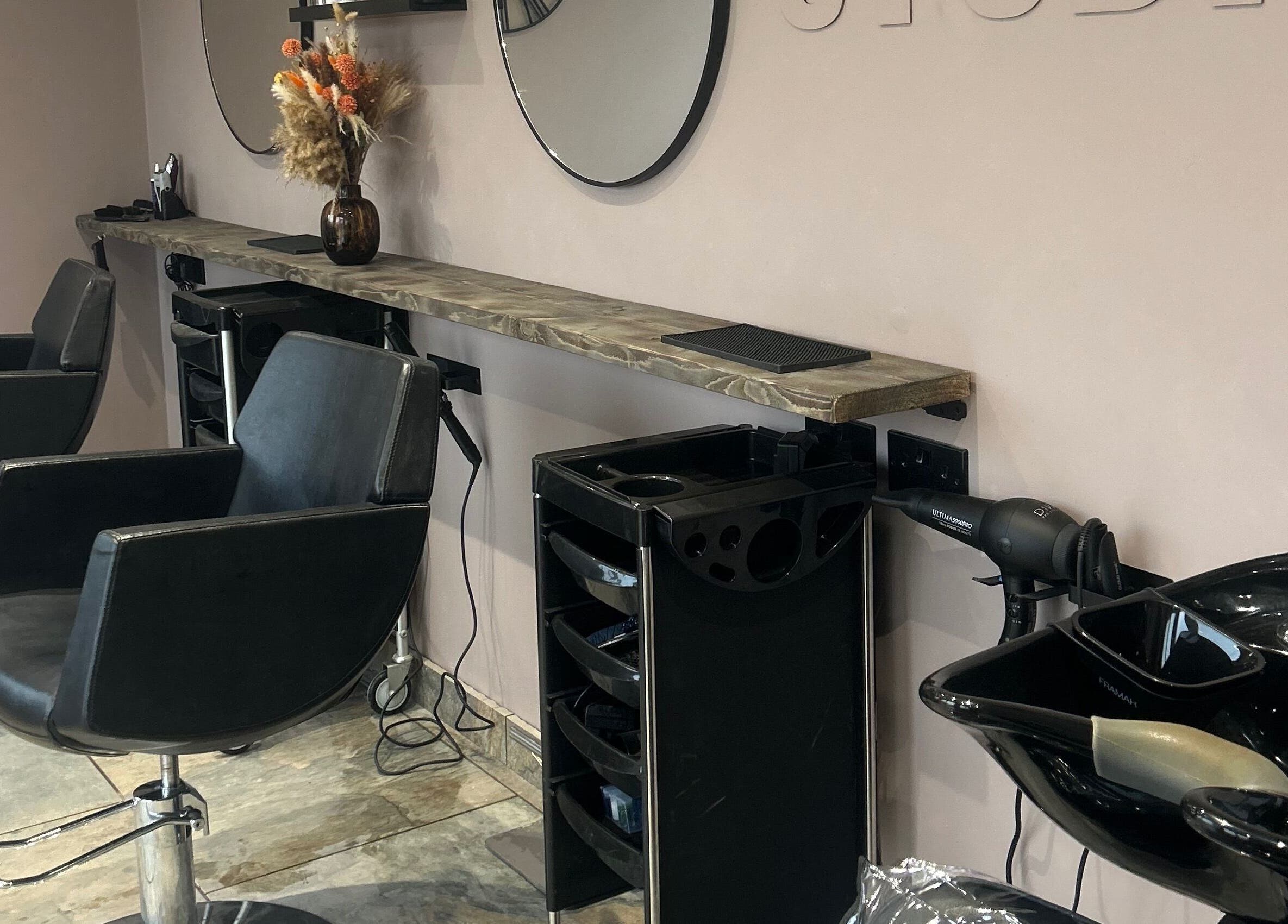 Stylish interiors of The Hair Studio in Ellesmere Port, England, GB with modern styling chairs and mirrors.