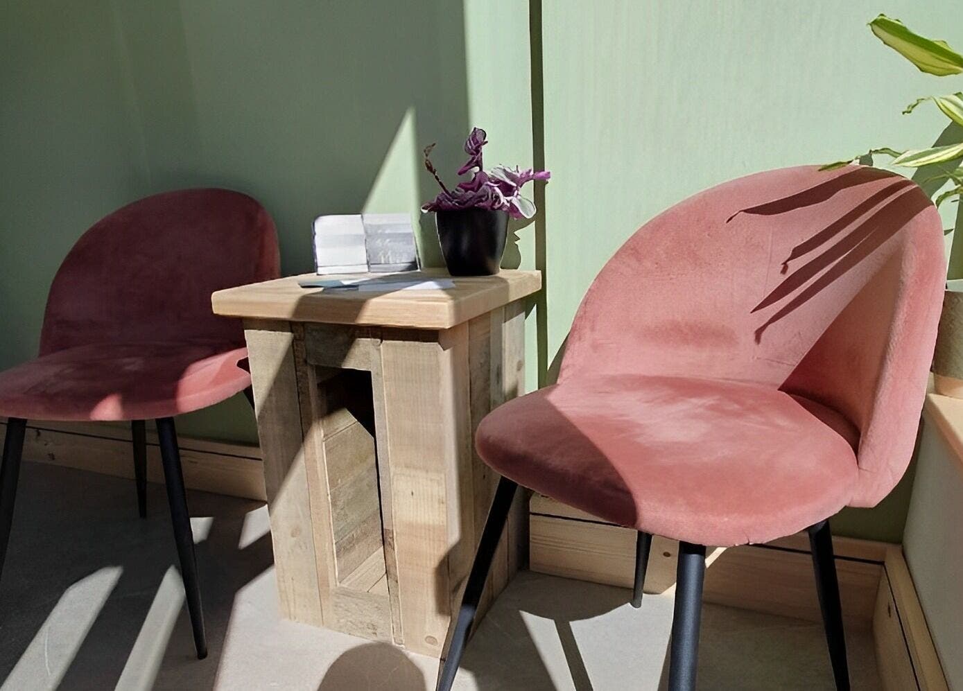 Inviting seating area at Miah’s Aesthetics, Eastbourne, England, GB with green walls and pink chairs.