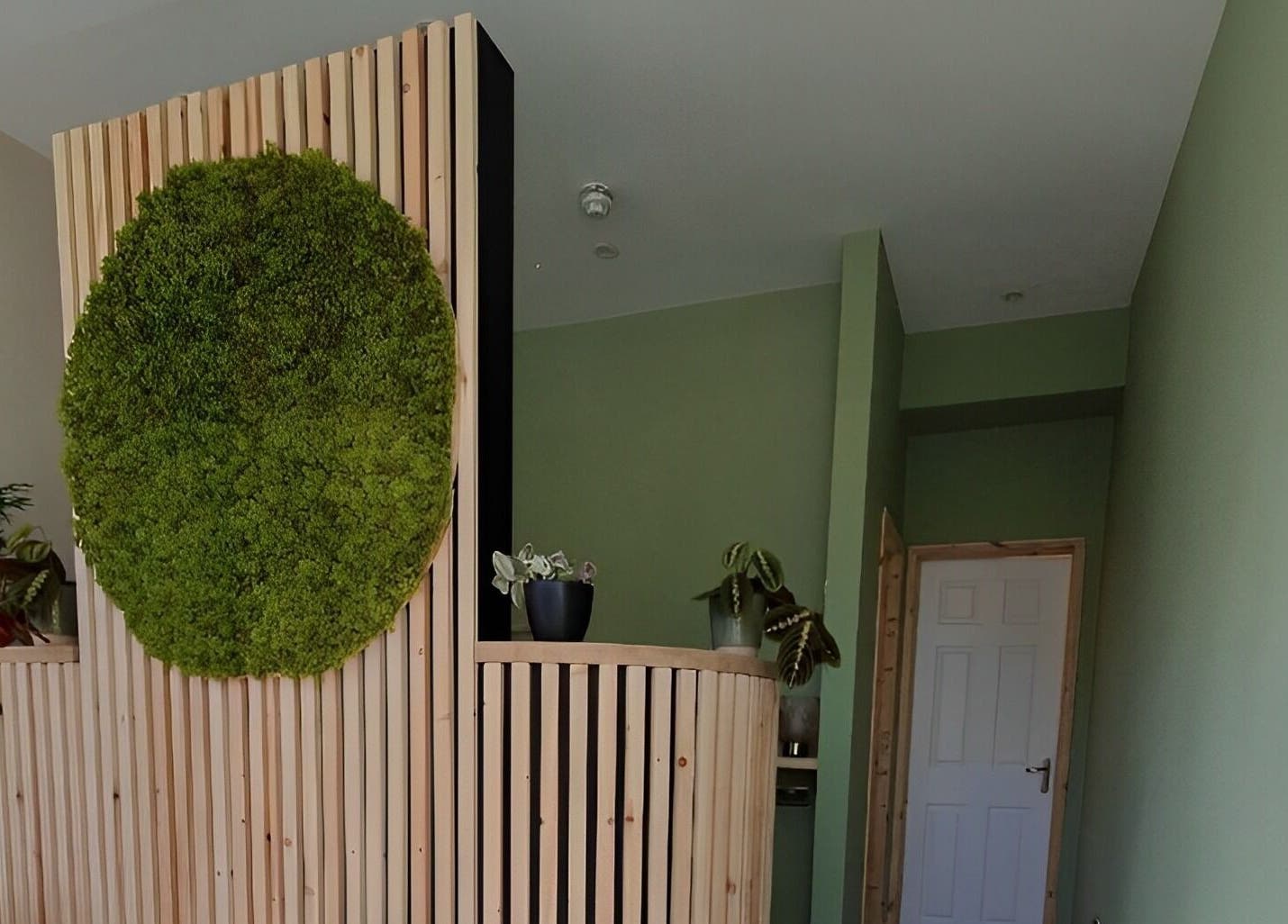 Moss wall design at Miah’s Aesthetics, Eastbourne, England, GB. Wooden accents enhance the natural decor.