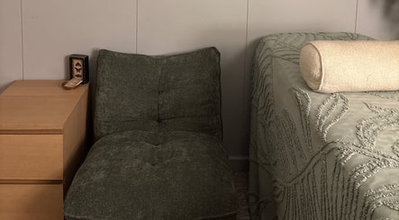 Cozy massage room at Glee Lash, Koongamia, Western Australia, AU with a plush chair and wooden side table.