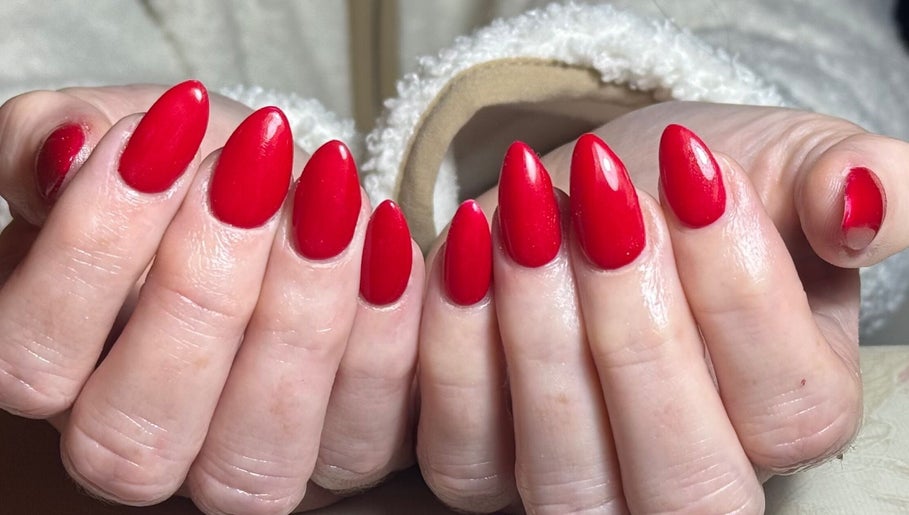Bright red manicured nails showcasing artistry at The Beauty Hut, Bourne, England, GB.
