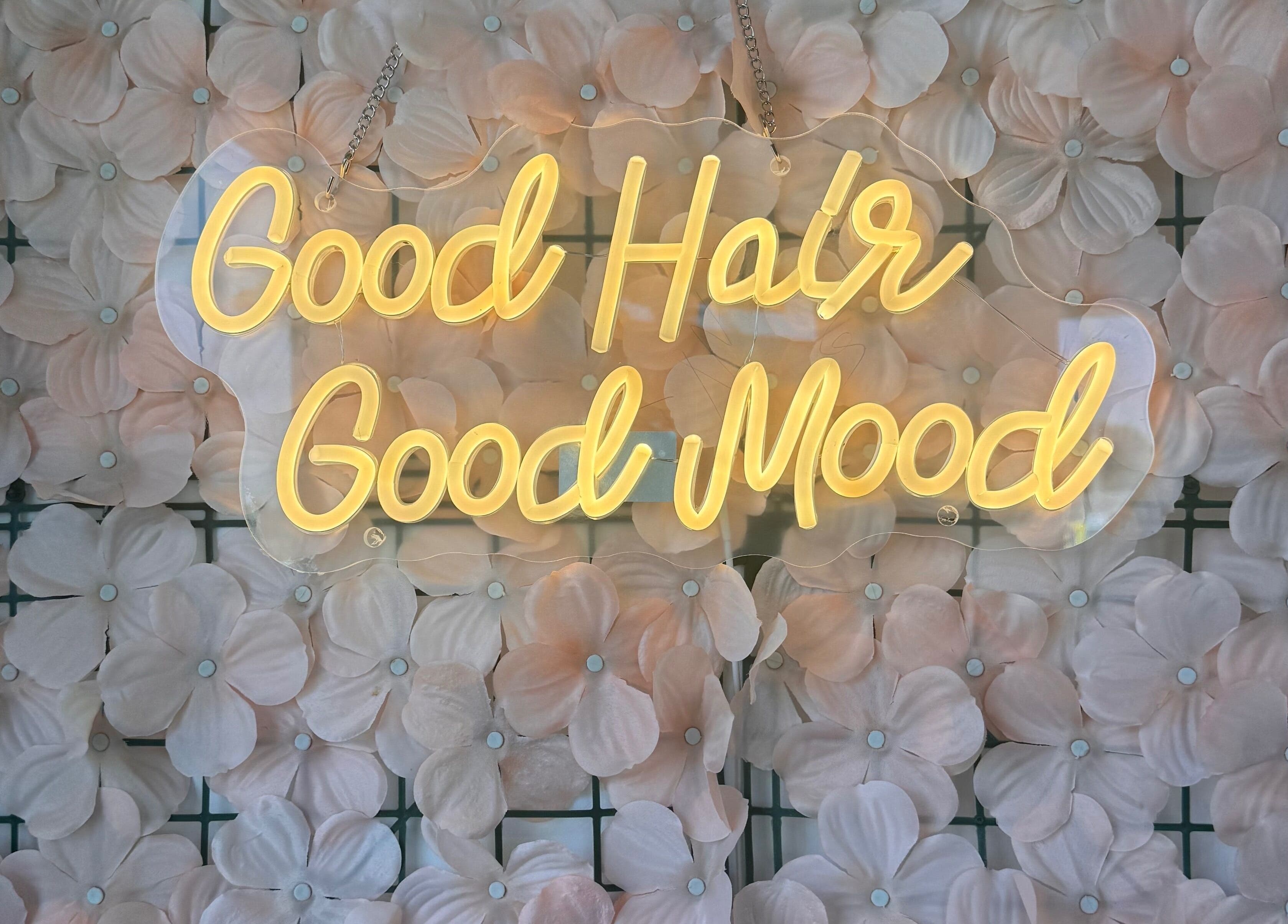 Neon 'Good Hair Good Mood' sign at TeeBeauty World, Manchester, England, GB on a floral wall.