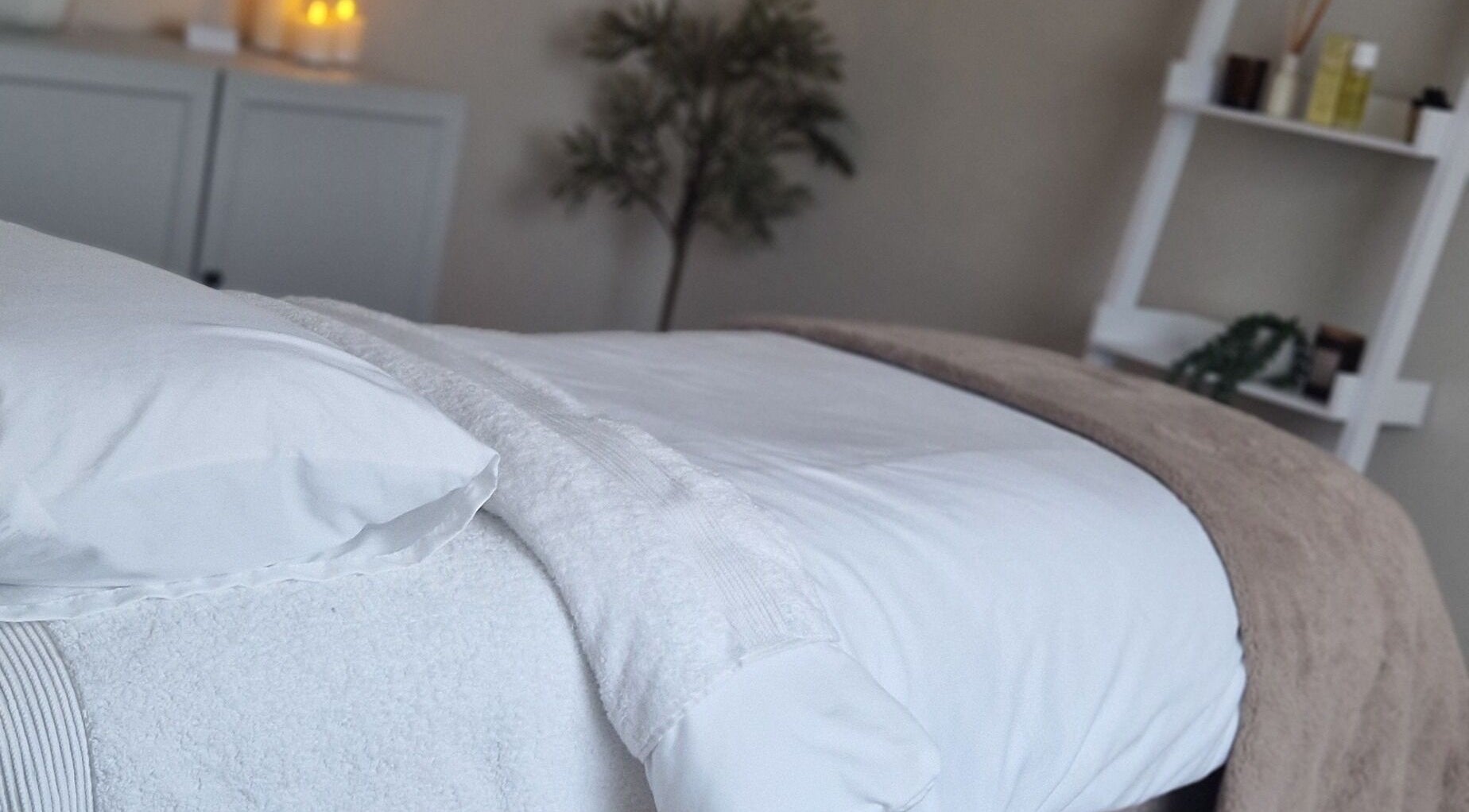 Tranquil massage room at Soul Serenity Beauty & Wellness, Newborough, England, GB, featuring a cozy bed and candles.