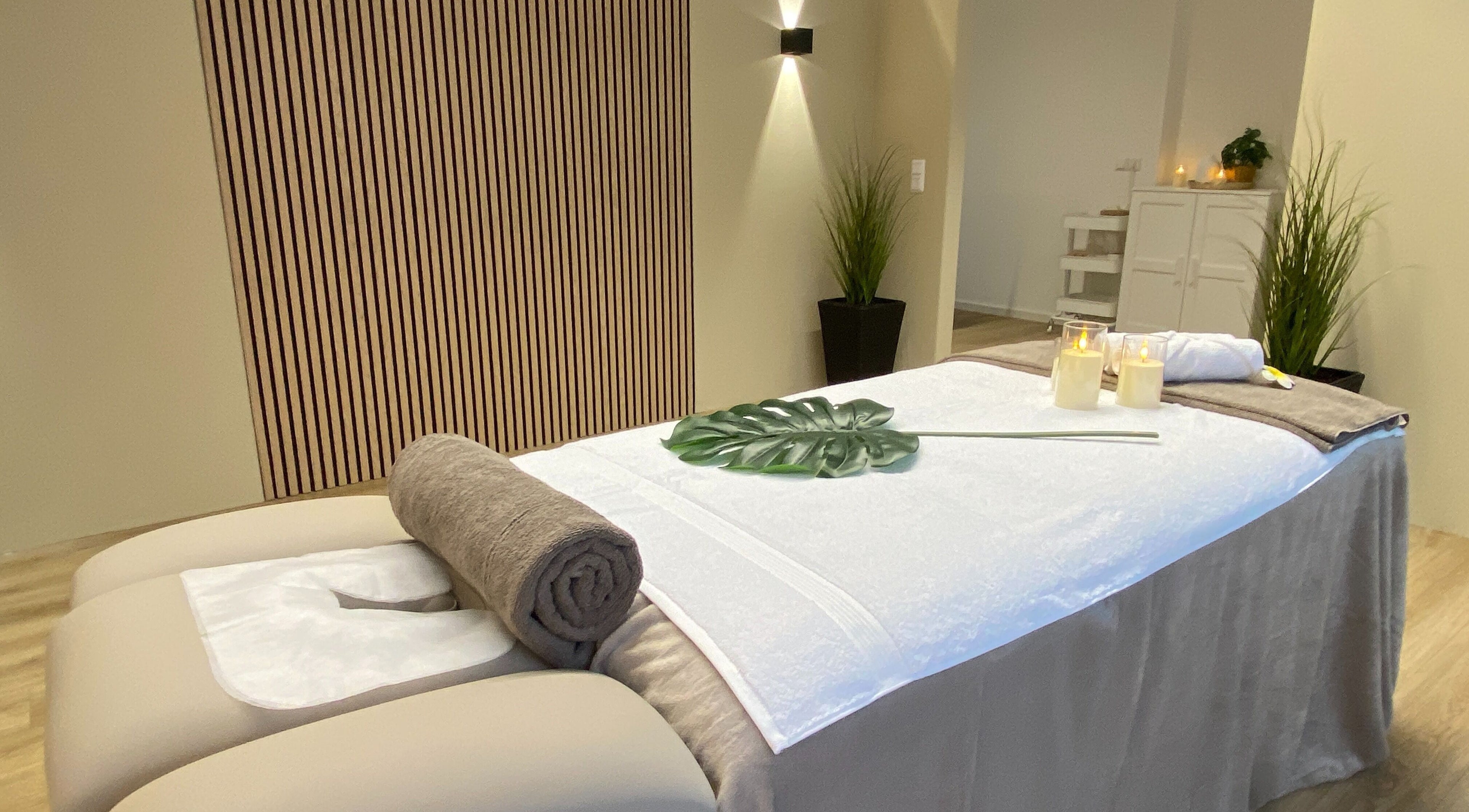 Massagebett im Sense Thai Massage & Boutique Spa in Tübingen, Baden-Württemberg, DE, umgeben von Kerzen und Pflanzen.