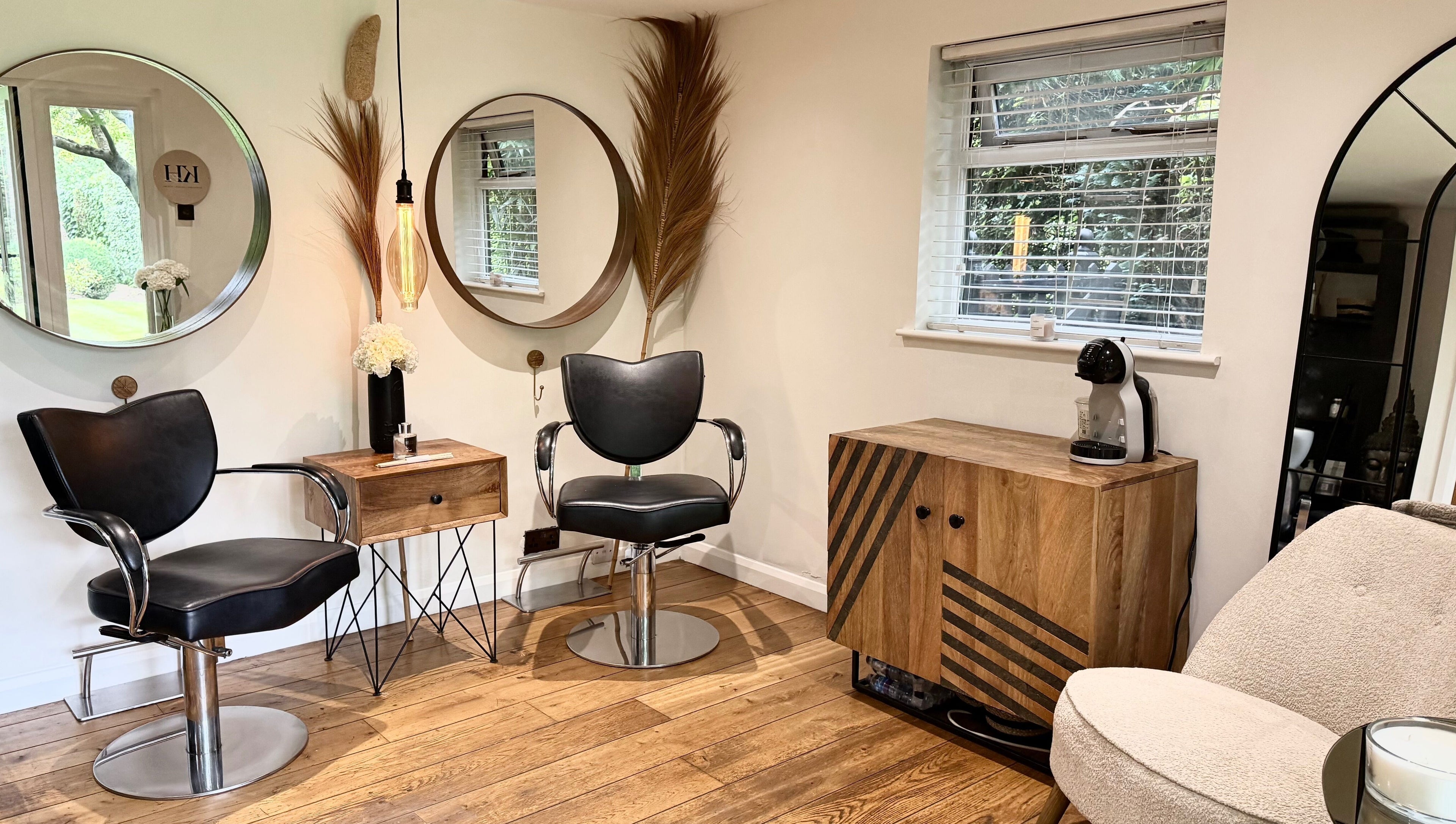 Modern salon seating area in KH Hair, Edenbridge, England, GB with stylish mirrors and wood accents.