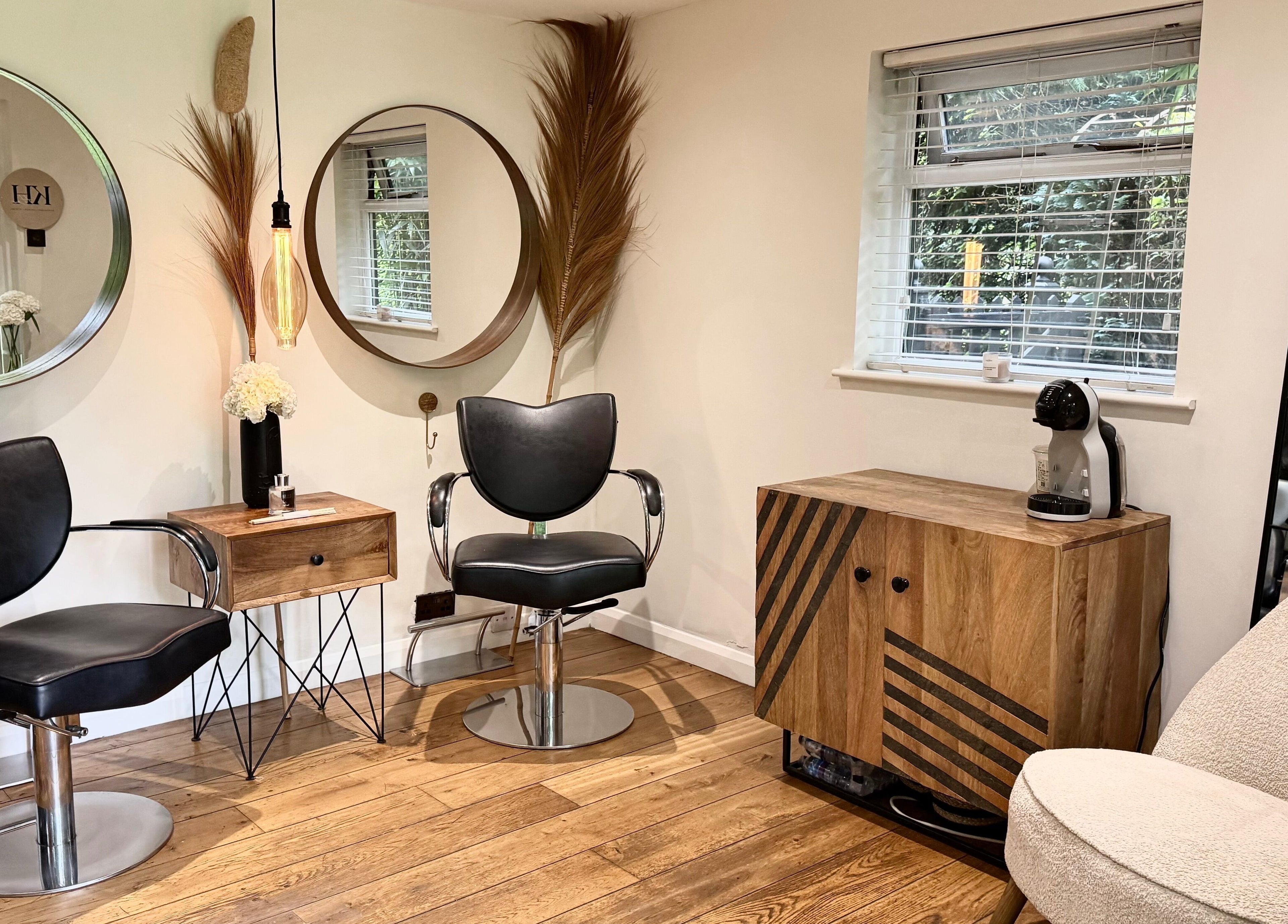 Modern salon seating area in KH Hair, Edenbridge, England, GB with stylish mirrors and wood accents.