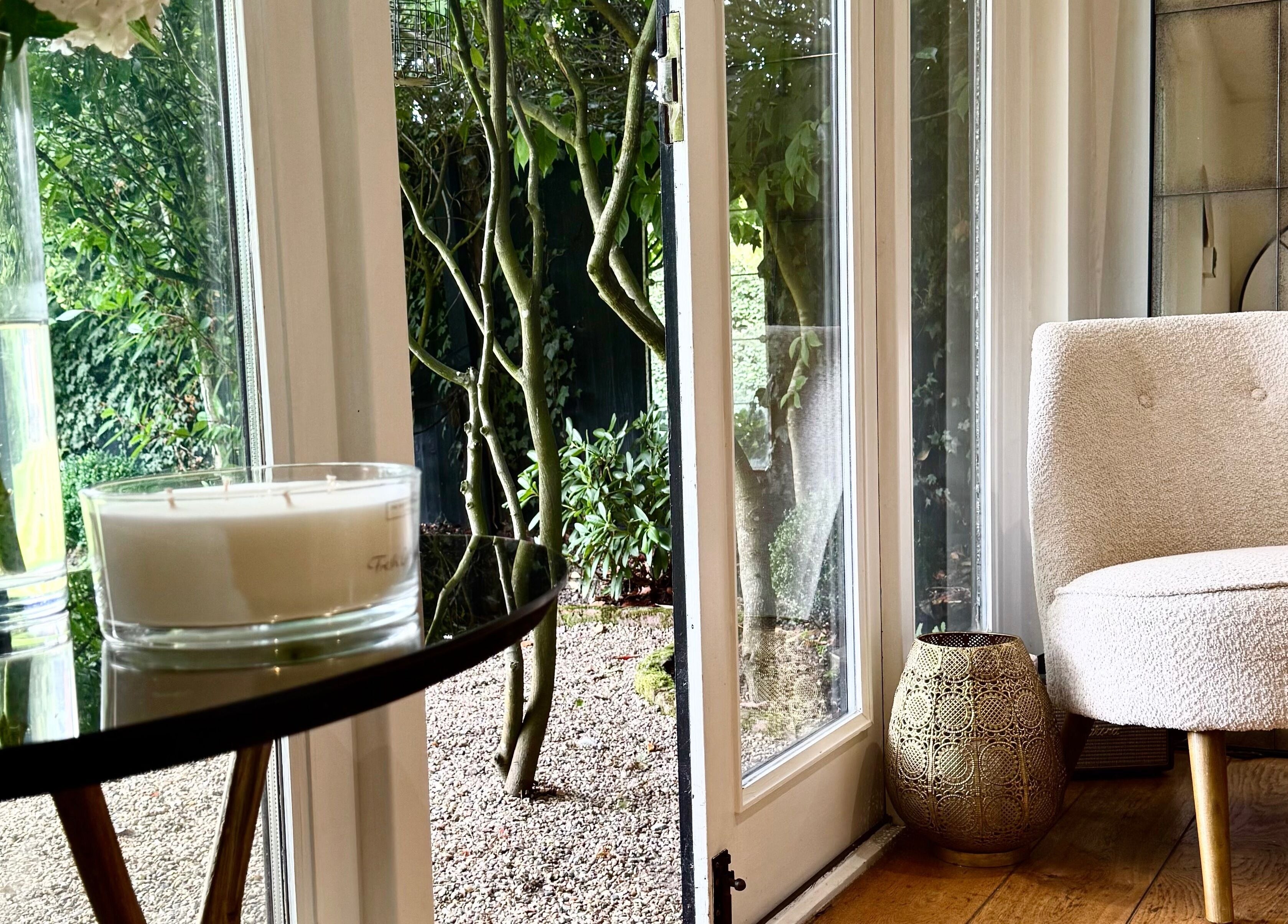 Cozy chair and candlelit ambiance at KH Hair, Edenbridge, England, GB, overlooking garden view.