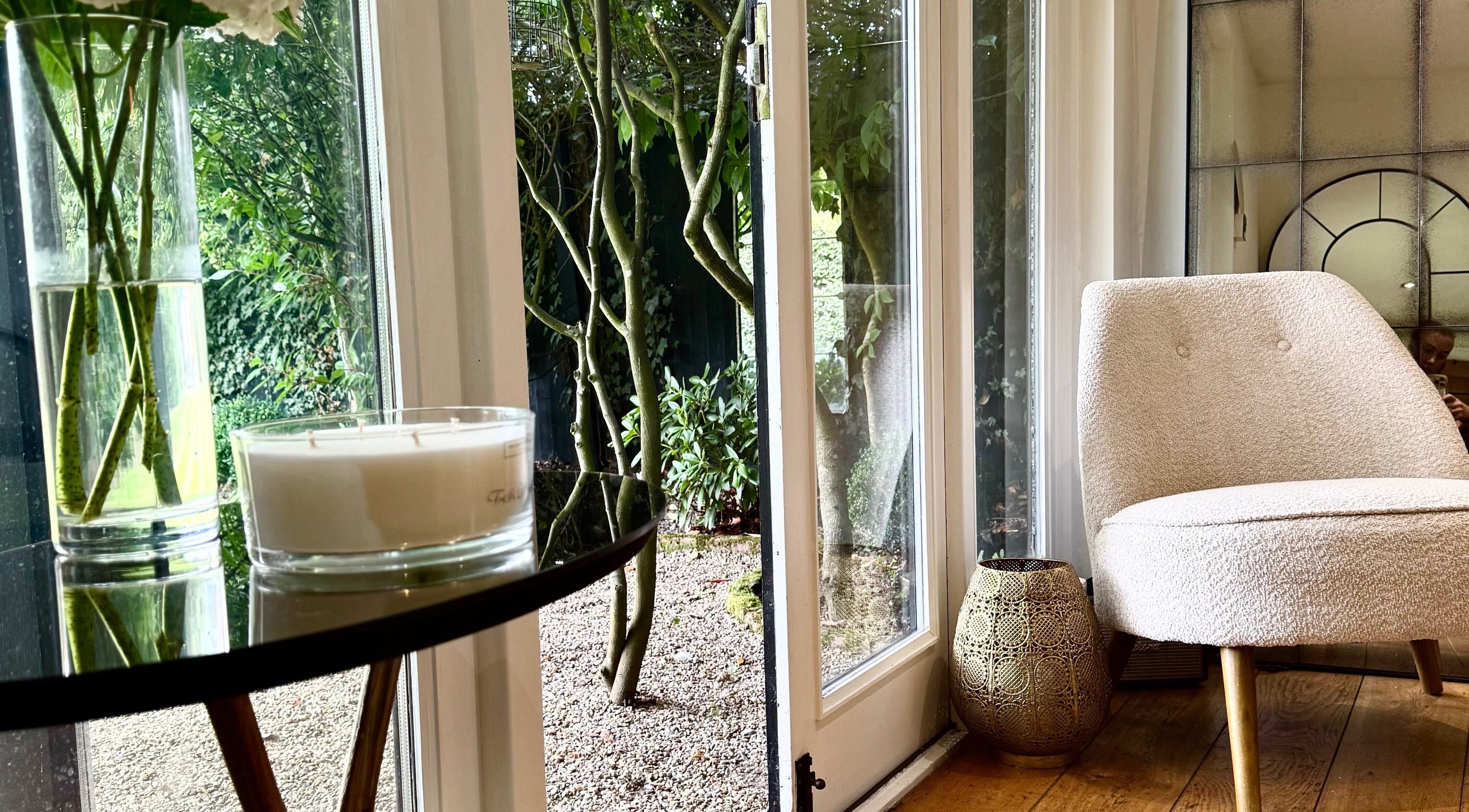 Cozy chair and candlelit ambiance at KH Hair, Edenbridge, England, GB, overlooking garden view.