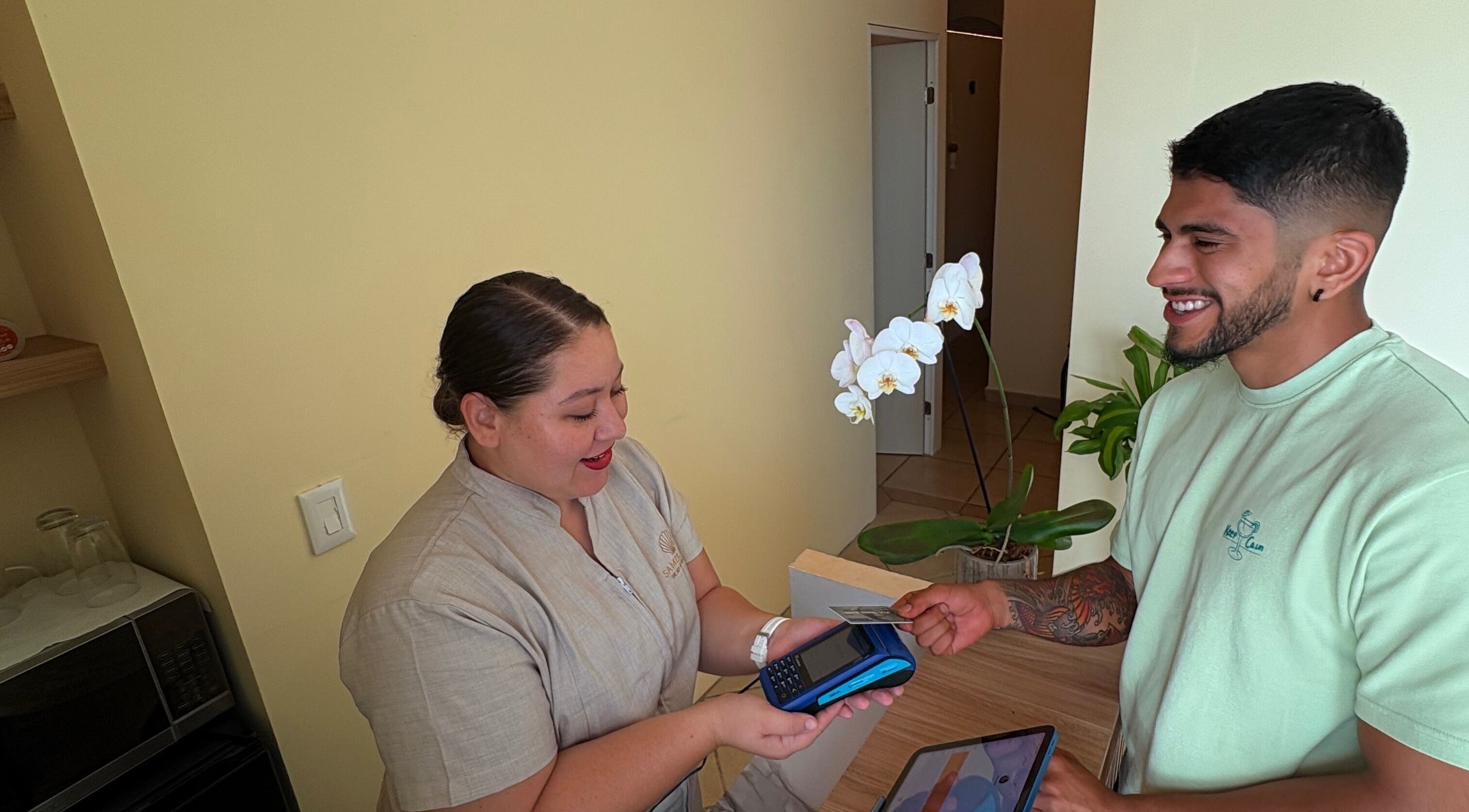 Recepcionista de Samer Spa en Puerto Vallarta, MX, atendiendo a un cliente con una tarjeta.