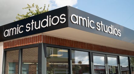 Modern facade of Amic Studios in Birstall, England, featuring sleek signage and glass windows.