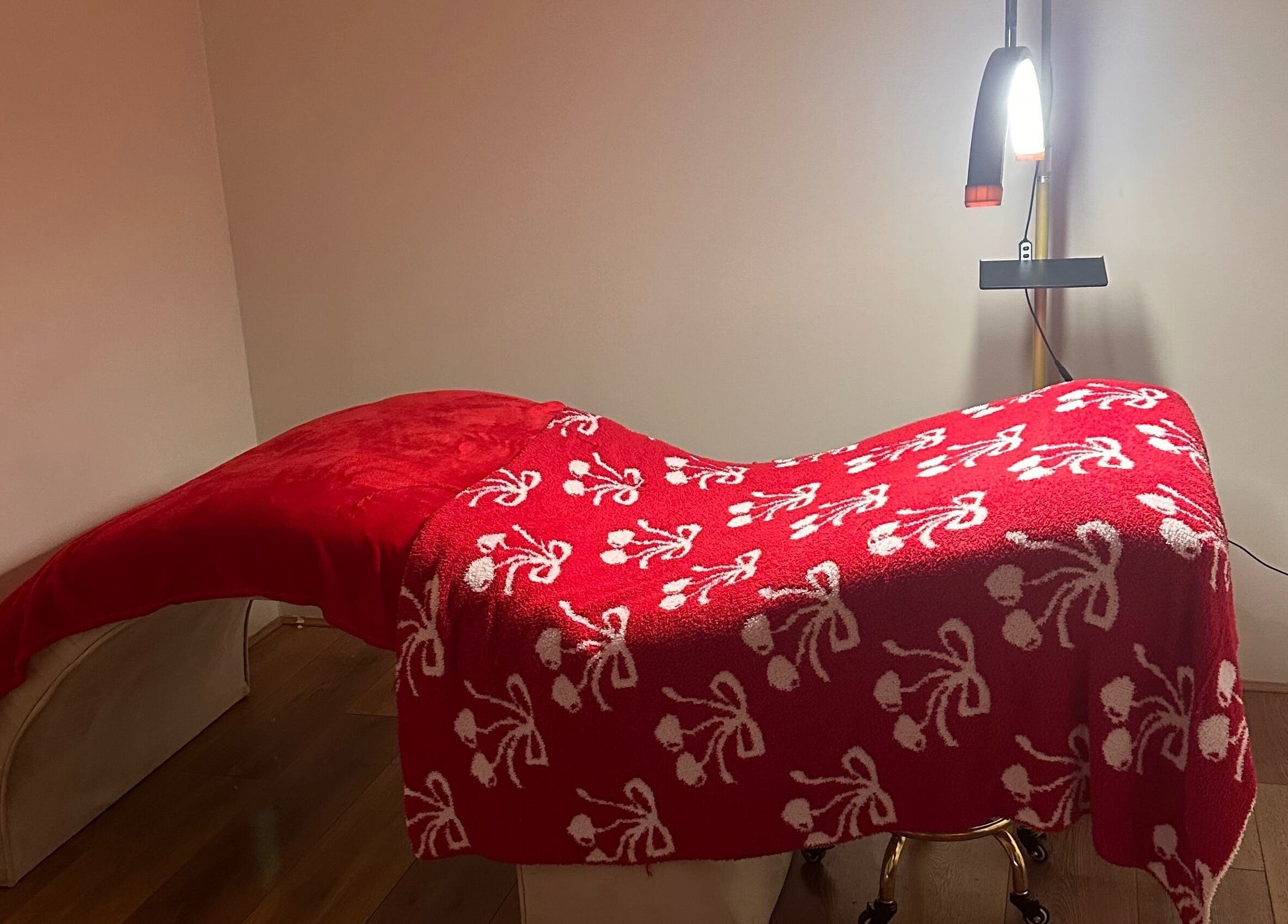 Elegant treatment bed with red floral blanket at The Beauty Bar by Chloe, Kirkcaldy, Scotland, GB.