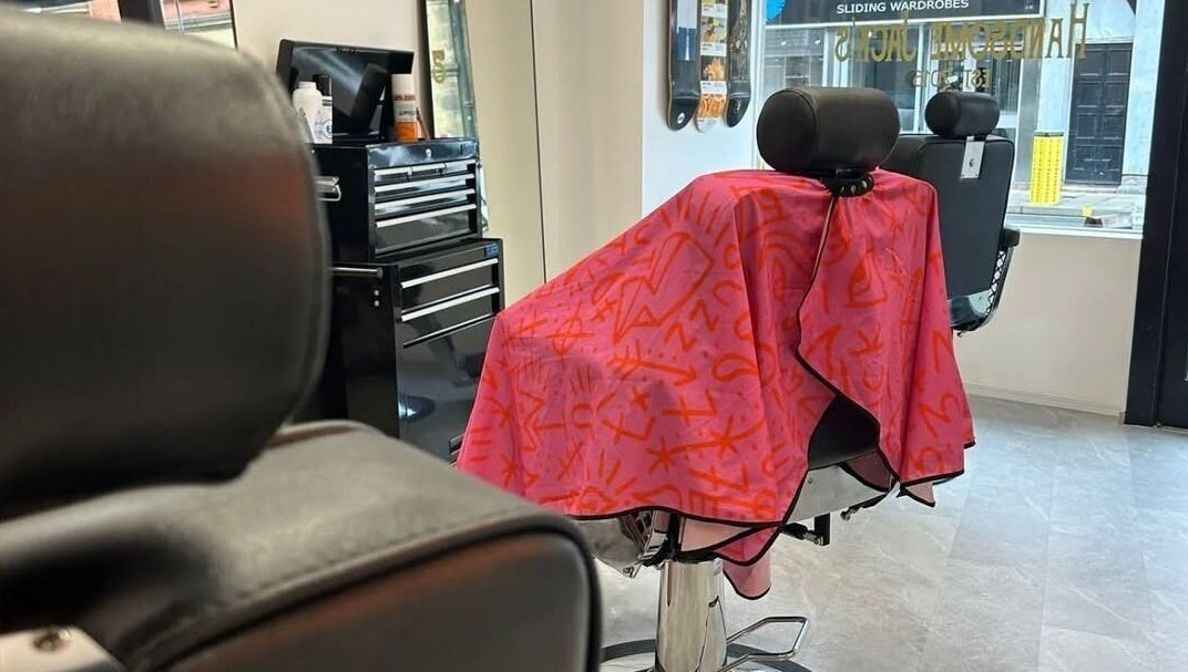 Barber chair draped with colorful cape at Handsome Jacks Whitley Bay, Whitley Bay, England, GB.