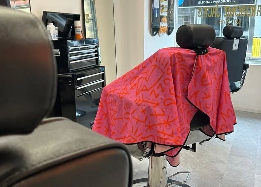 Barber chair draped with colorful cape at Handsome Jacks Whitley Bay, Whitley Bay, England, GB.