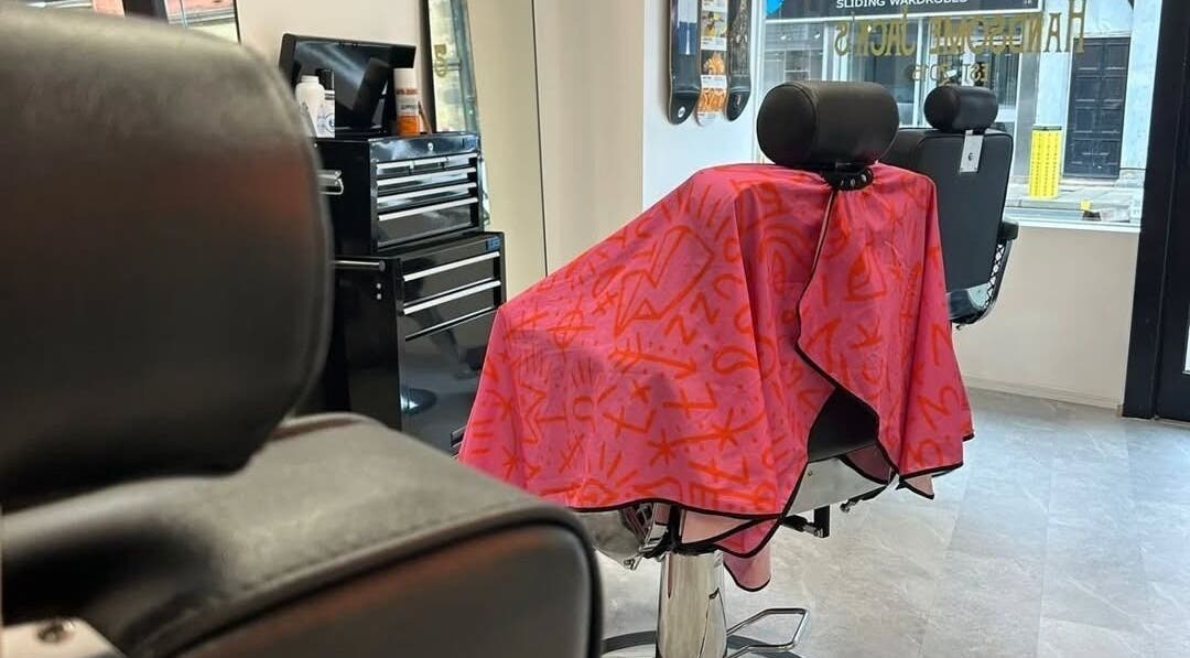 Barber chair draped with colorful cape at Handsome Jacks Whitley Bay, Whitley Bay, England, GB.