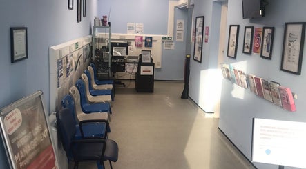 Bright waiting area at GP Healthcare Alliance, Hadleigh, England with chairs and informative wall displays.