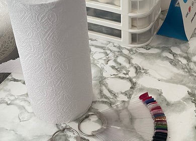 A neat marble countertop at Fefesnailboutique in Akasia, Gauteng, ZA with paper towels and nail polish samples.