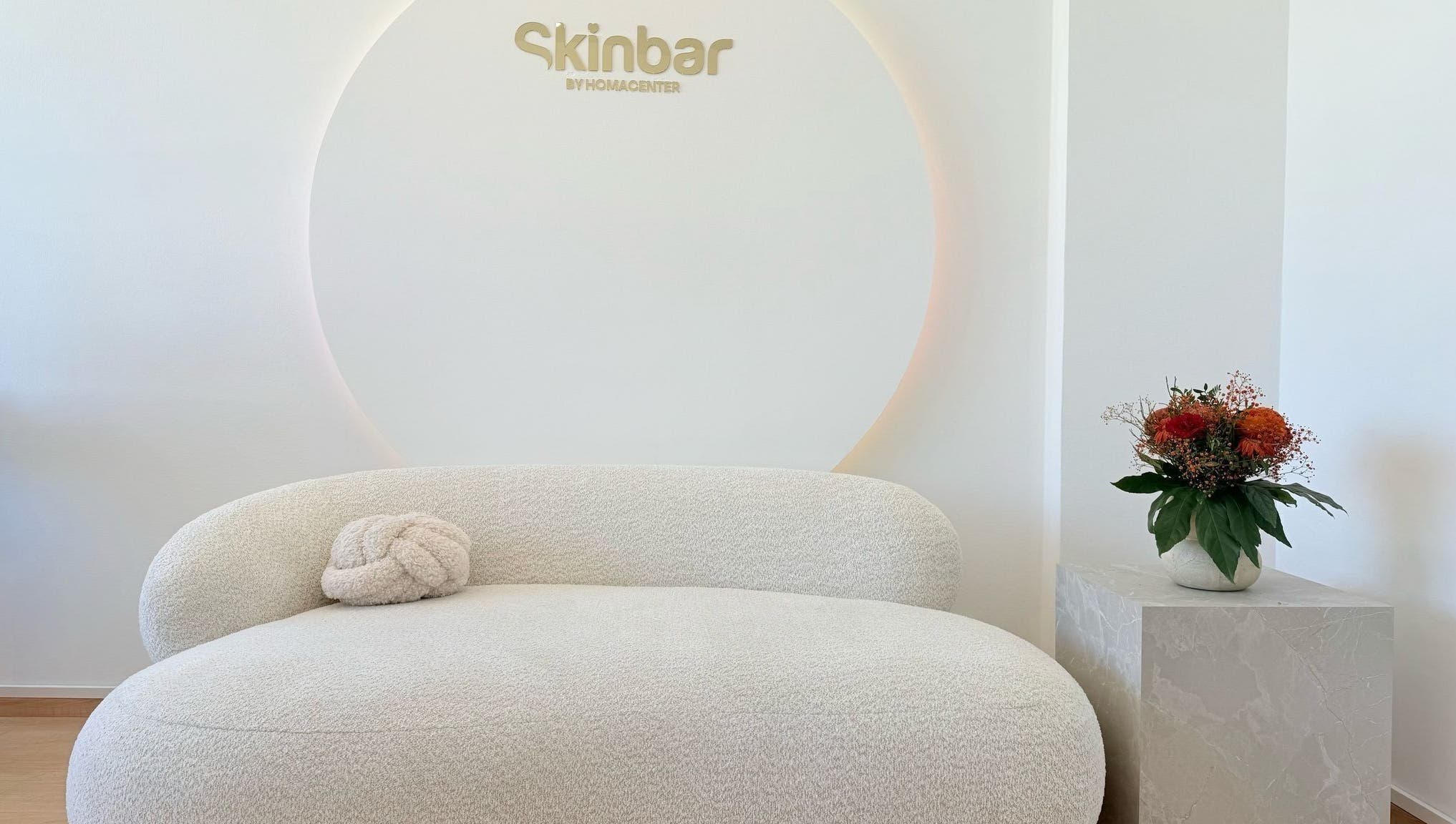 Eleganter Wartebereich bei Nailbar Wien, Wien, AT, mit bequemer weißer Couch und Blumendekor.