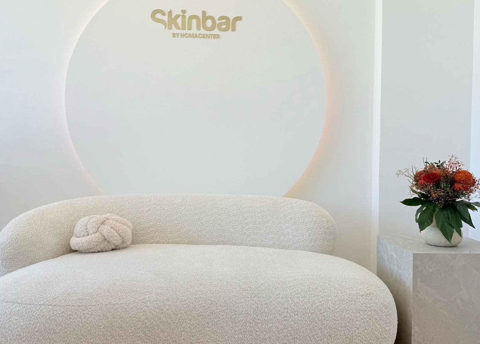 Eleganter Wartebereich bei Nailbar Wien, Wien, AT, mit bequemer weißer Couch und Blumendekor.
