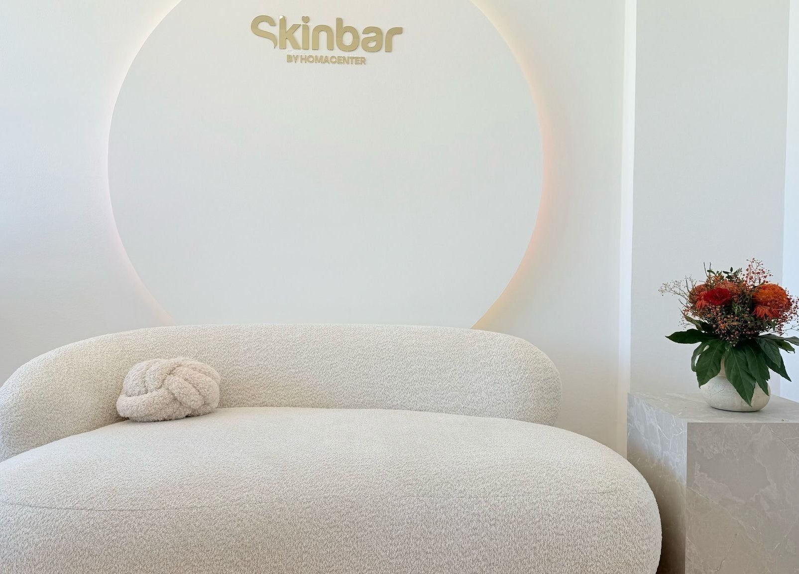 Eleganter Wartebereich bei Nailbar Wien, Wien, AT, mit bequemer weißer Couch und Blumendekor.