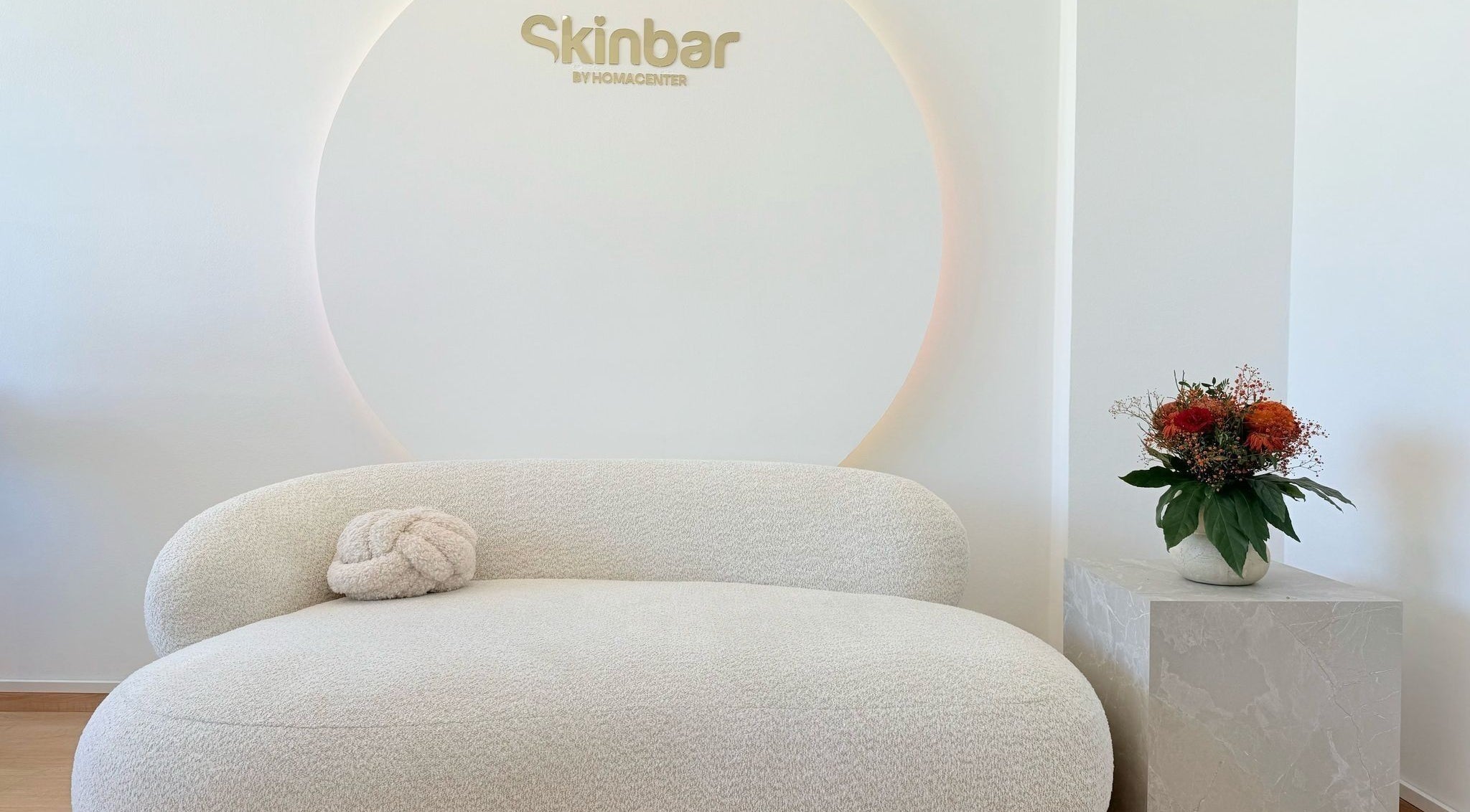Eleganter Wartebereich bei Nailbar Wien, Wien, AT, mit bequemer weißer Couch und Blumendekor.