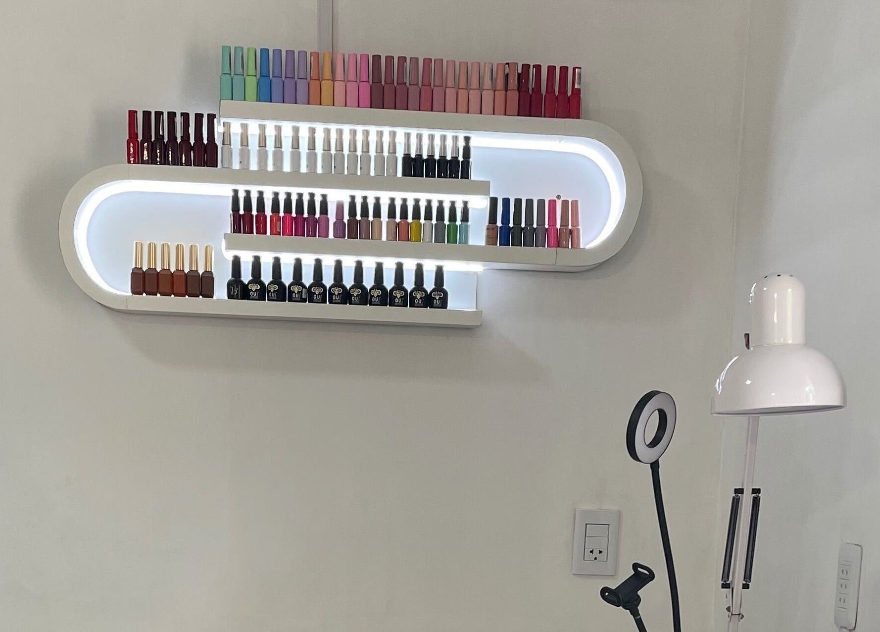 Estante de esmaltes iluminado en romSo, Luque, Central, PY, destacando variedad de colores.